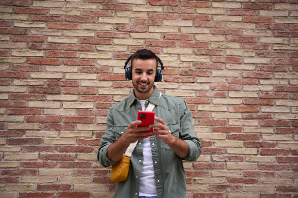 istock Copy space of handsome millennial man using mobile leaning against brick wall. Addicted technology. 2089813525