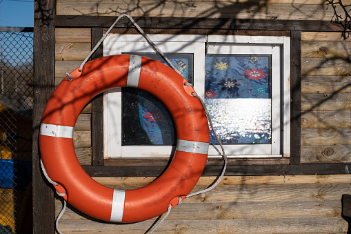 A lifebuoy hangs near the window at the boat station. The waves on Lake Almaznoye are reflected in the window. Kyiv. Ukraine.