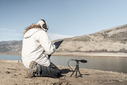 Sustainability practices. Man does field-based studies using AI driven ecoacoustic approaches in bioacoustics research.