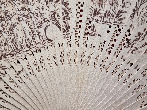 Opened perforated bamboo fan with a pattern. Abstract background