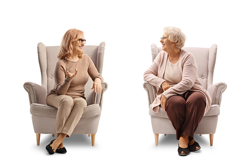 Elderly mother and daughter sitting armchairs and talking isolated on white background
