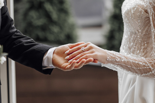 Cropped shot of an unrecognizable newlywed couple holding and showing their rings on their wedding day
