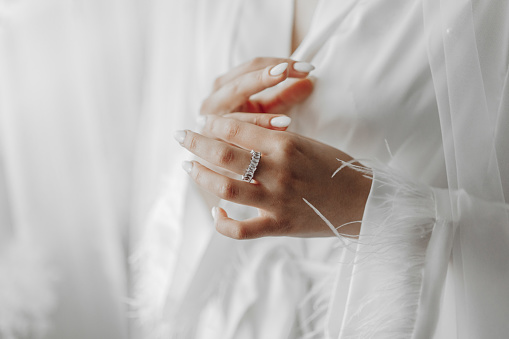 the bride holds a diamond engagement ring. Beautiful hands of the bride.