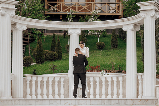 The bride and groom embrace near the Roman-style columns. An exquisite wedding