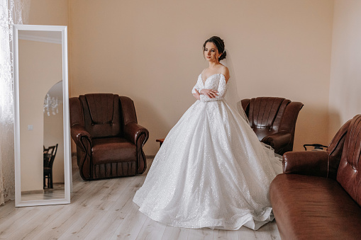 The bride in her wedding dress poses in her room. Portrait of the bride.