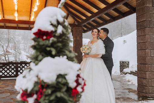 Horizontal shot of a beautiful bride and groom walking and enjoying the park on a snowy winter day. Winter wedding.