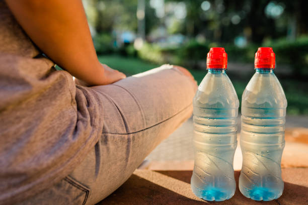 istock Plastic bottle next to a person sitting in the park with blurred background and copy space 2090084832