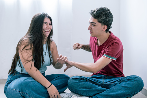 A young Latino couple enjoys a playful and happy interaction, sharing a laugh indoors