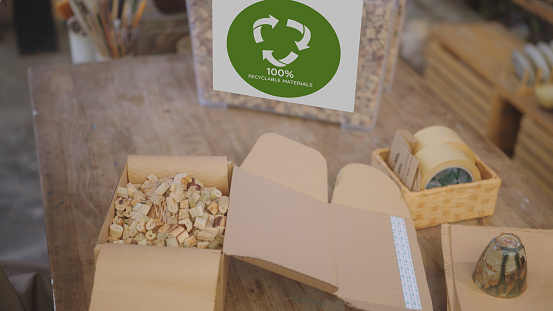 Close up of SME business owner chooses to use eco-friendly packaging, utilizing recyclable cardboard and water hyacinth cushioning for their pottery, showcasing an environmentally conscious and waste reduction approach