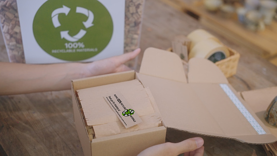 Close up of SME business owner chooses to use eco-friendly packaging, utilizing recyclable cardboard and water hyacinth cushioning for their pottery, showcasing an environmentally conscious and waste reduction approach