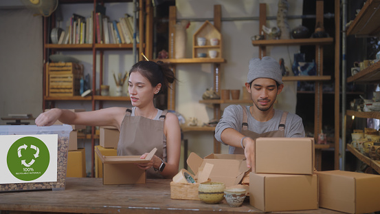 SME business owner chooses to use eco-friendly packaging, utilizing recyclable cardboard and water hyacinth cushioning for their pottery, showcasing an environmentally conscious and waste reduction approach. Southeast Asian and Thai ethnicity model, Males and Females, including white people, 25-29 years
