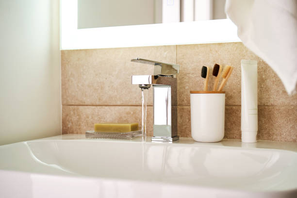 istock Bathroom sink with toothbrushes and running water. 2090347418