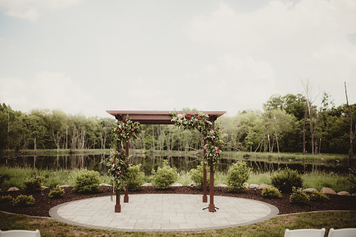 Outdoor wedding with water in the background and flowers on arch