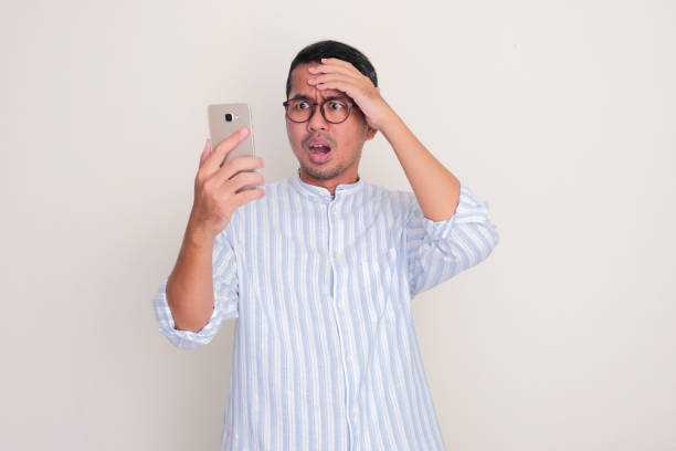 istock Adult Asian man showing shocked expression when looking his mobile phone 2090484473