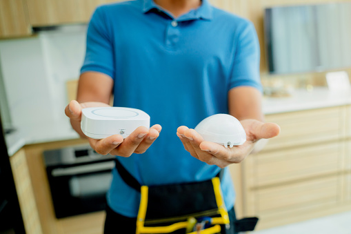 A technician installs a security alarm siren and motion sensor detector