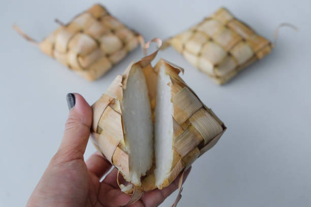 istock Unrecognizable hand holding a sliced open ketupat 2090500252