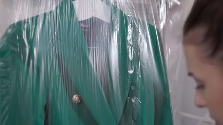 Woman Packing Suit With Plastic Using Packing Machine For Laundry Shop. slow motion shot