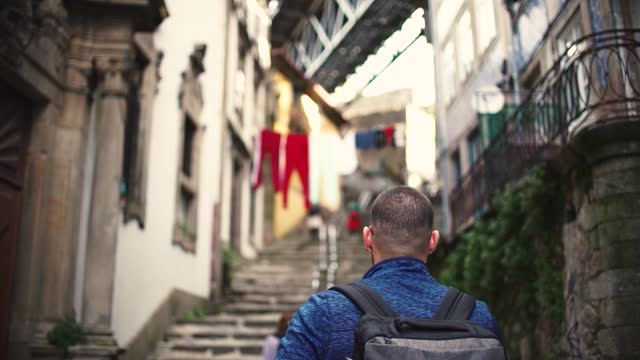 Tourist man walking though poor neiborhood narrow alley in Porto District, Portugal