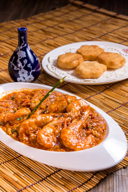 istock stir fried prawn seafood with spicy chilli crab egg thick gravy sauce and deep fried man tofu bun on bamboo wood table tea pot asian Chinese halal food restaurant banquet cuisine cafe menu 2090604986