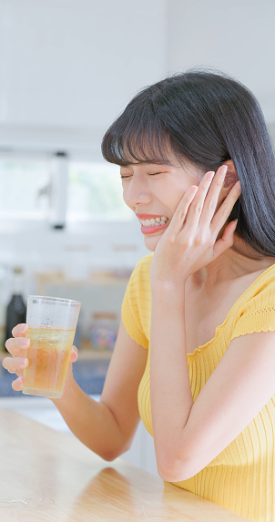 Closeup side asian woman drinks iced drink and feels tooth pain - she has sensitive teeth problem