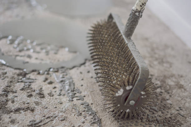 istock plasterer during floor covering works with self-levelling cement mortar, uses a needle roller 2090625278