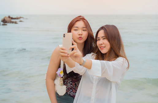 summer, holidays, vacation and happiness concept - Close friend couple taking selfie with smartphone over sea background.