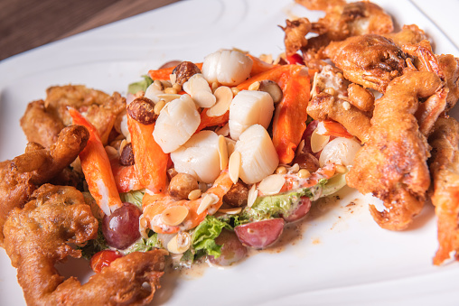 chinese and western mixed seafood combination cold platter with deep fried soft shell crab scallop salad on wood table asian restaurant banquet halal food cafe menu