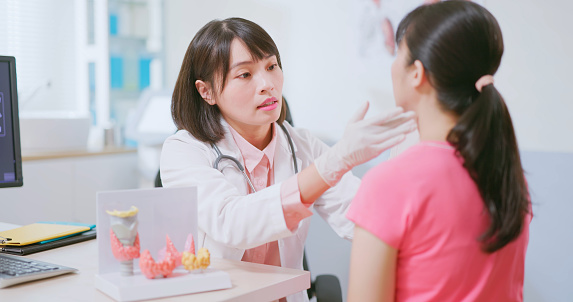 Closeup view of asian physician palpating patient thyroid gland in the clinic - cancer related examinations