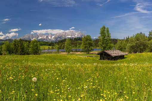 Mountain hut in front of mountain lake with the Kaiser Mountains in the background