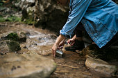 Woman washing a coffee mug in mountain stream on hiking trip
