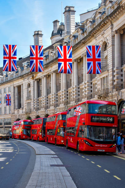 Busses and Flags Four London buses underneath the British flags. city of london flag stock pictures, royalty-free photos & images