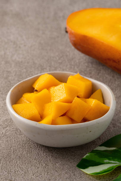 istock Fresh chopped, diced mango cubes on gray table background with tropical leaf. 2090792935