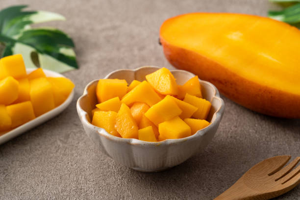 istock Fresh chopped, diced mango cubes on gray table background with tropical leaf. 2090795359