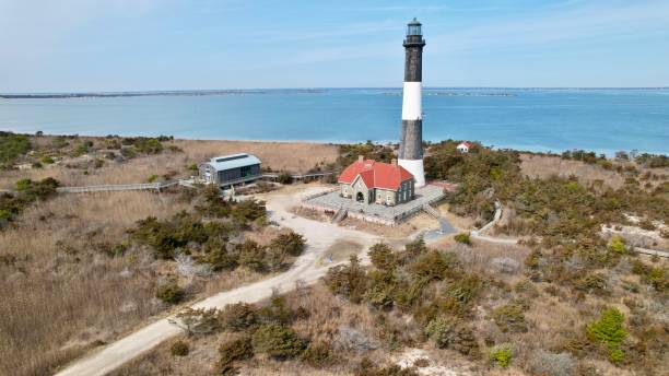 a lighthouse surrounded by grass and trees next to the ocean