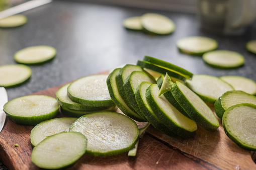 Chopped courgette slices on a wooden cutting board.