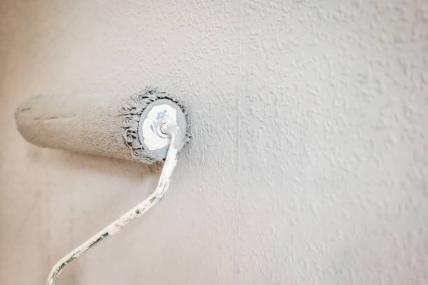 istock Paint roller extendable pole over painted woodchip wallpaper wall during home renovation in england uk 2090813830