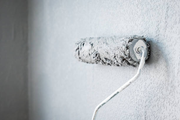 istock Paint roller extendable pole over painted woodchip wallpaper wall during home renovation in england uk 2090813835