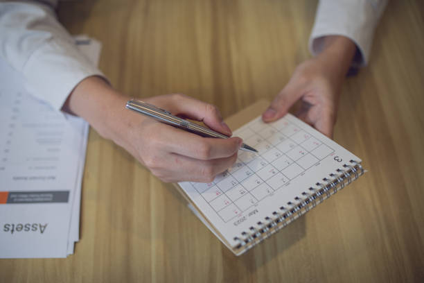 istock Professional setting a schedule in a planner with a pen, amidst a business-focused workspace 2090823988