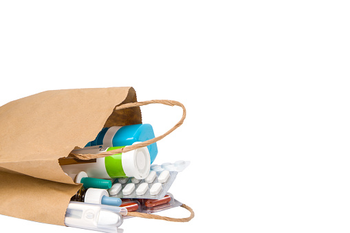 Paper bag with pills and capsules isolated on white background with copy space