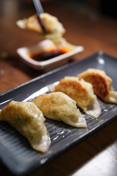 istock In the cropped image, a woman's hand is using chopsticks to pick up gyoza dumplings. 2090887158