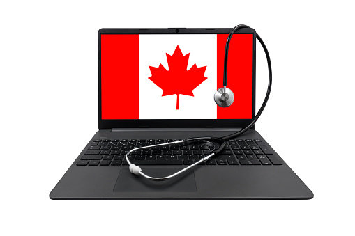 Laptop with Canada flag on screen and medical stethoscope, isolated on white background. Canada's healthcare system concept