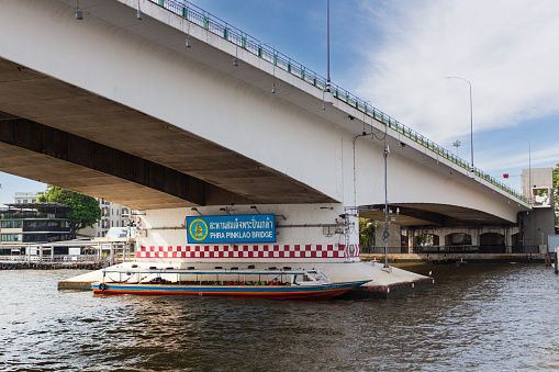 Bangkok, Thailand - 30 December, 2023: Empty tourist boat parked under Phra Pinklao bridge at Bangkok, Thailand. Somdet Phra Pinklao bridge across the Chao Phraya River.
