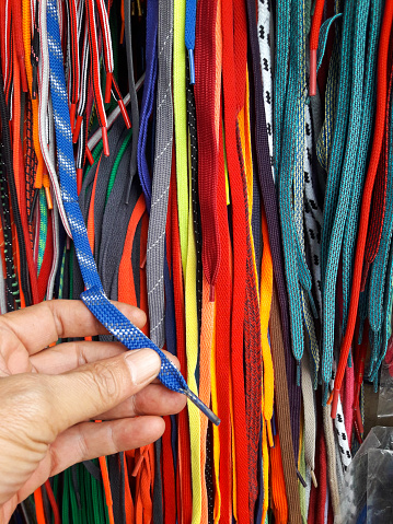 People who are choosing shoelaces in a shop that provides various colors and patterns.