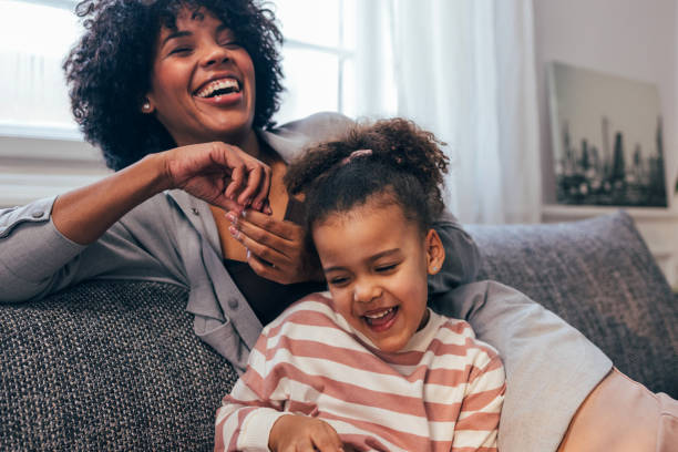 joyful african american mother and daughter laughing together indoors - life events laughing women latin american and hispanic ethnicity imagens e fotografias de stock