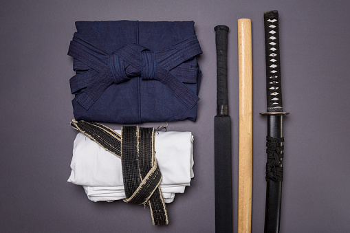 The concept of minimalism in traditional martial arts. Clothes and training weapons for fencing on a gray background.