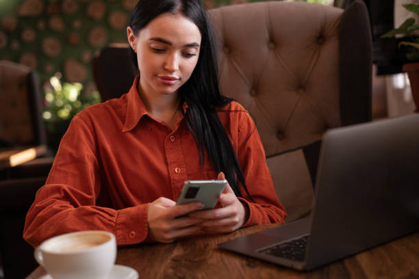 istock Female student learns online on laptop computer, prepares for exam, uses smartphone chatting with friends, spends free time at cafe 2091008995