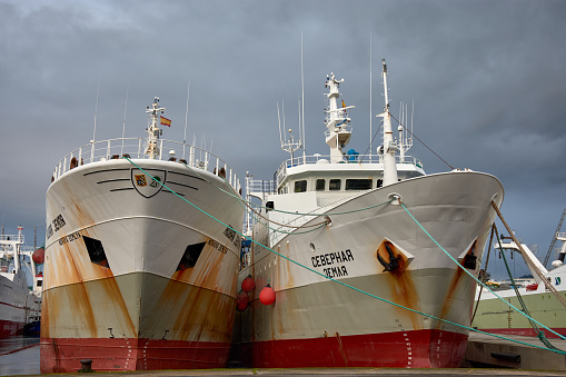 Vigo, Pontevedra, Spain; December,18,2022; Two freezer trawlers seen from the bow with rust docked in the port of Vigo on a cloudy day