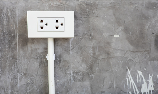 The white box plug socket is installed on the plaster wall in the lobby style.