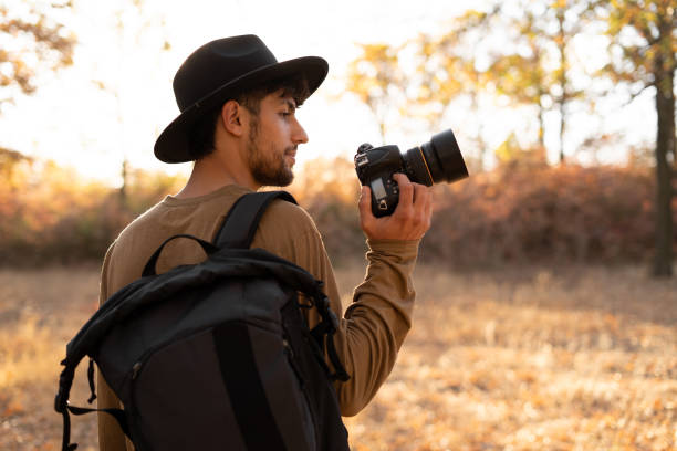 konzept der naturfotografie. professioneller naturfotograf mit digitalkamera und herbstwald im hintergrund - behind photographer men mountain climbing stock-fotos und bilder