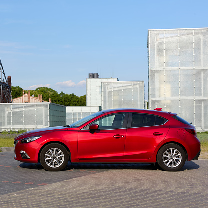 Red Mazda 3 with the buildings of the Silesian Museum in the background. Katowice, Poland 22.05.2016